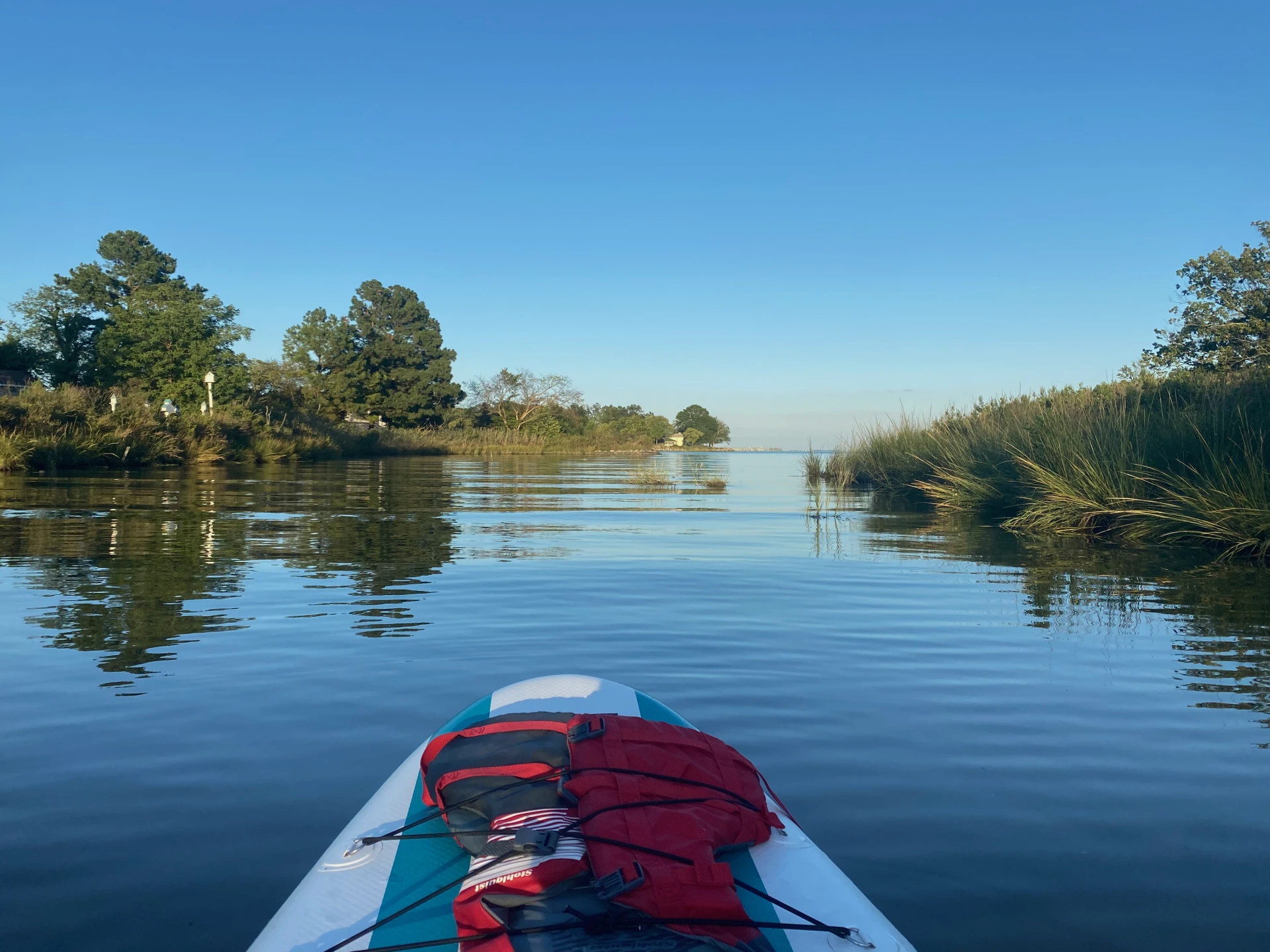 View from a stand-up paddleboard gliding through calm water toward the Chesapeake Bay at Chesapeake Paradise in Maryland.